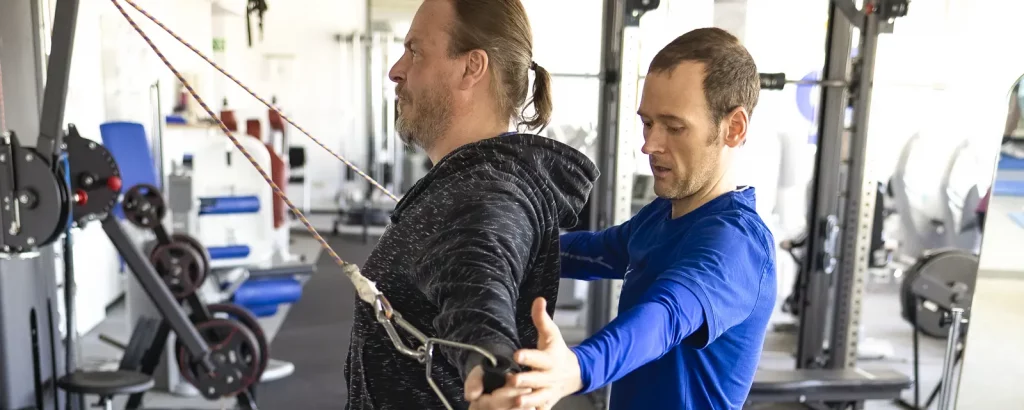Ein Trainer prüft die Körperhaltung eines Klienten